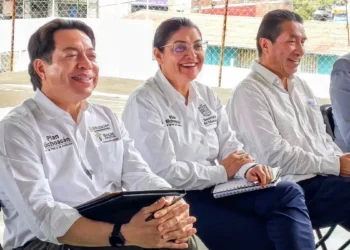Cuatro funcionarios en reunión en un espacio abierto, con vestimenta formal y sonriendo, en un evento de educación.