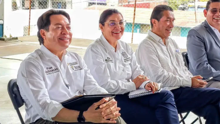 Cuatro funcionarios en reunión en un espacio abierto, con vestimenta formal y sonriendo, en un evento de educación.