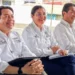 Cuatro funcionarios en reunión en un espacio abierto, con vestimenta formal y sonriendo, en un evento de educación.