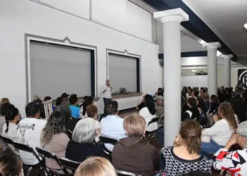 Conferencista en un taller de tanatología frente a una audiencia en un auditorio.
