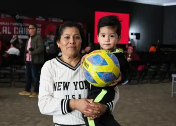 Mujer y niño con balón en evento de apoyo a familias con niños con cáncer en Michoacán.