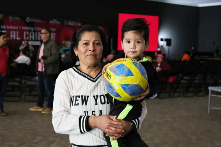 Mujer y niño con balón en evento de apoyo a familias con niños con cáncer en Michoacán.