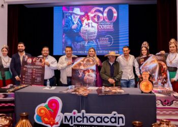 Grupo de personas en escenario con cartel y pantalla que conmemora 60 años de feria en Santa Clara del Cobre.
