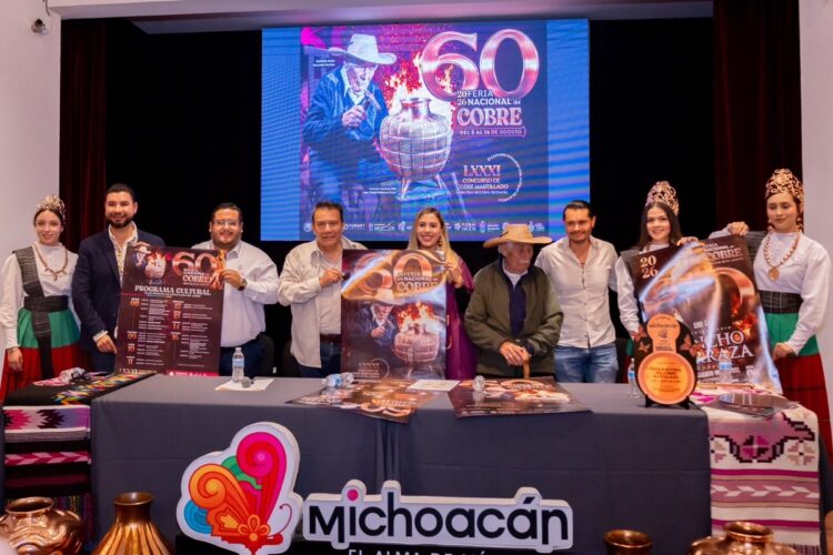 Grupo de personas en escenario con cartel y pantalla que conmemora 60 años de feria en Santa Clara del Cobre.