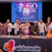 Grupo de personas en escenario con cartel y pantalla que conmemora 60 años de feria en Santa Clara del Cobre.
