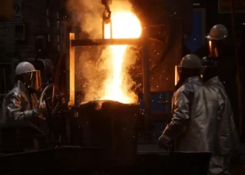 Trabajadores en una fundición de metal en Michoacán, con fuego y chispas en proceso de fundición.