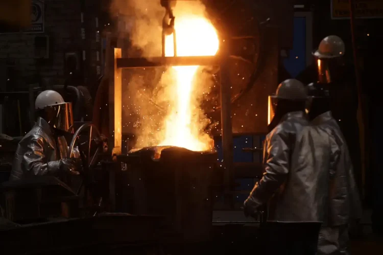 Trabajadores en una fundición de metal en Michoacán, con fuego y chispas en proceso de fundición.