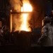 Trabajadores en una fundición de metal en Michoacán, con fuego y chispas en proceso de fundición.
