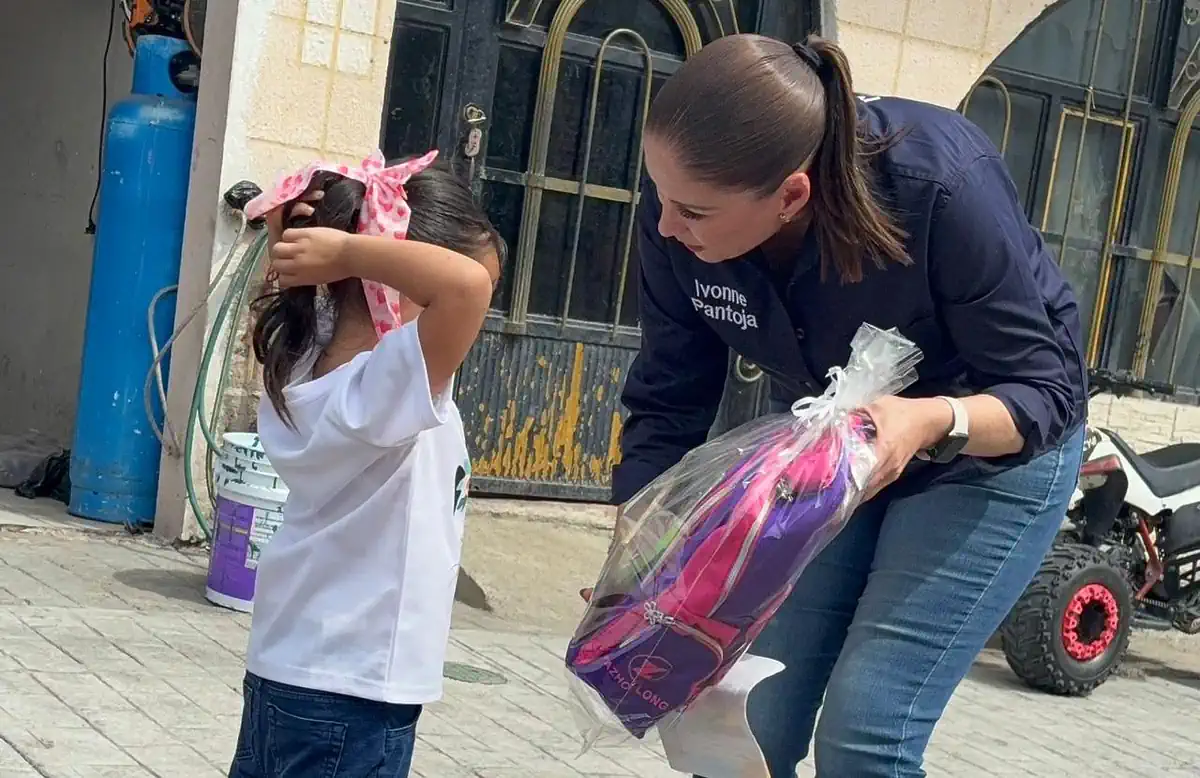 Niña recibe un regalo de una mujer durante evento infantil en Michoacán.