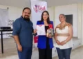 Tres personas en ceremonia de reconocimiento, una con certificado y regalo, en evento de familias de acogida en Michoacán.