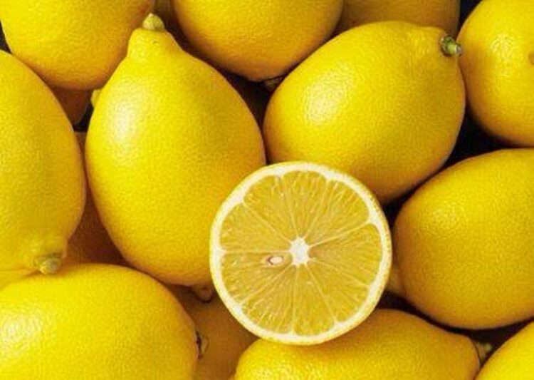 Limones amarillos frescos con uno partido mostrando su interior jugoso y brillante.