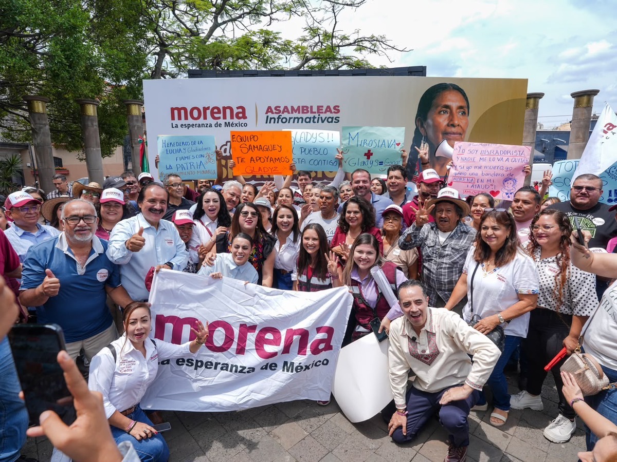 Grupo de personas con pancartas y banderas de Morena en una manifestación política en Michoacán y Jalisco.