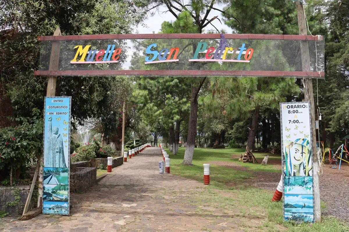 Puente peatonal en San Pedrito, Pátzcuaro, con cartel de horarios y señalización.