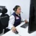 Mujer en centro de atención telefónica con auriculares y computadora, monitoreando llamadas para prevenir extorsiones.