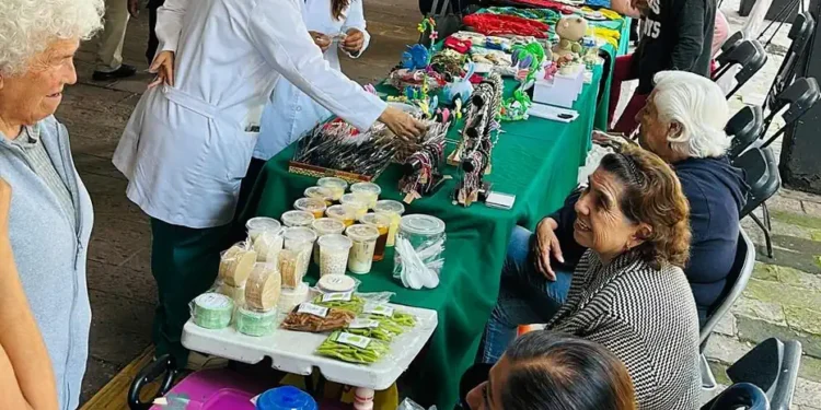 Adultos mayores y visitantes en mercado de artesanías en Michoacán, con puestos de productos tradicionales y artesanales.