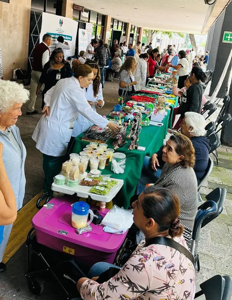 Adultos mayores y visitantes en mercado de artesanías en Michoacán, con puestos de productos tradicionales y artesanales.