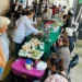 Adultos mayores y visitantes en mercado de artesanías en Michoacán, con puestos de productos tradicionales y artesanales.