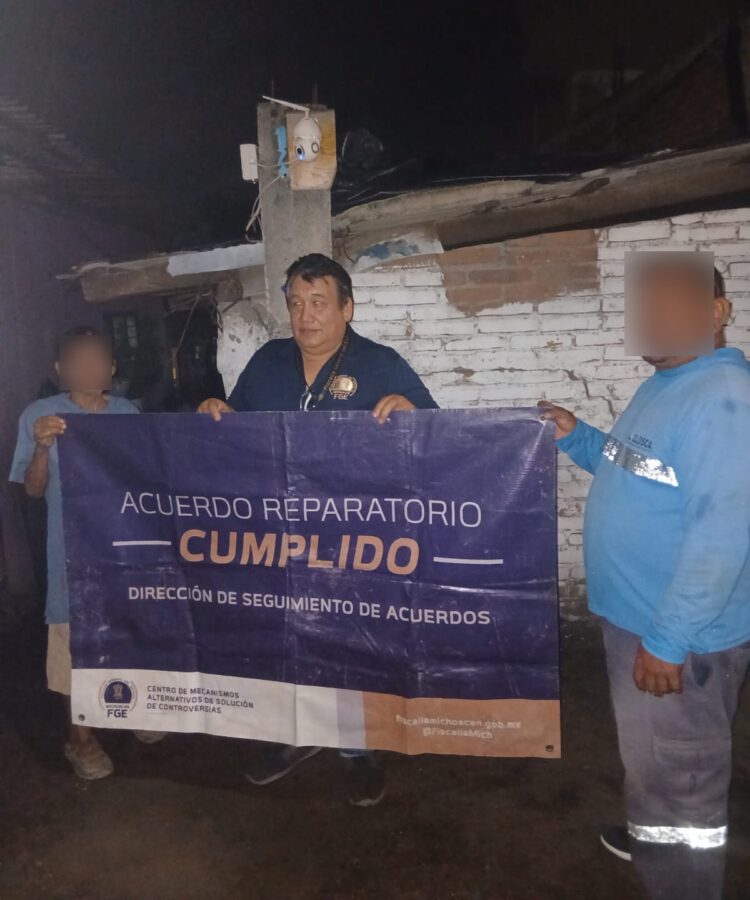 Autoridades y ciudadanos sostienen cartel de acuerdo cumplido en Michoacán durante la noche.