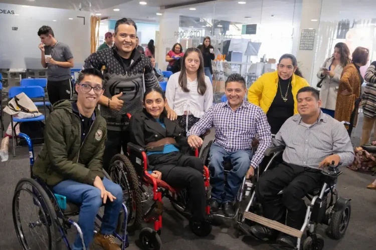 Grupo de personas con discapacidad en evento de apoyo social en un espacio cerrado.