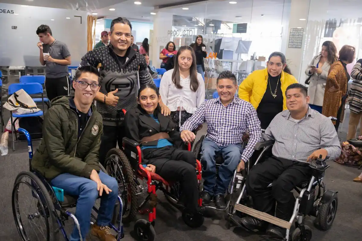 Grupo de personas con discapacidad en evento de apoyo social en un espacio cerrado.