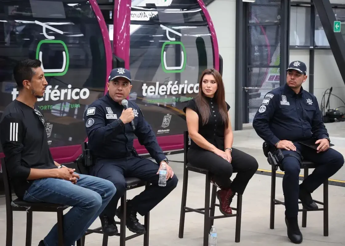 Cuatro oficiales y una mujer participan en un panel de discusión en un espacio público.