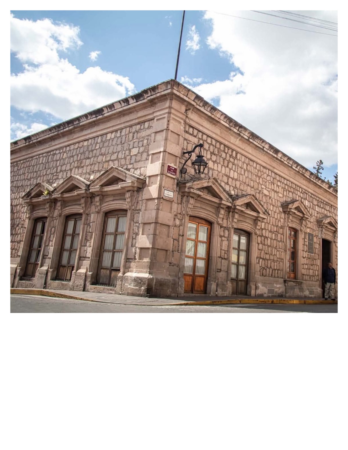 Edificio colonial de piedra con ventanas de madera y detalles ornamentales en Michoacán bajo cielo despejado.