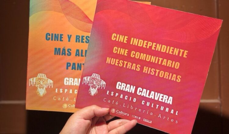 Una mano sostiene dos folletos coloridos de un espacio cultural llamado Gran Calavera.