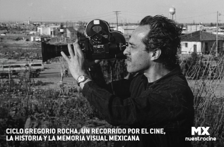 Un hombre sostiene y filma con una cámara de cine en blanco y negro al aire libre en un área urbana.