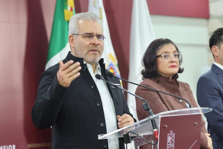Un hombre y una mujer están de pie frente a un podio con micrófonos durante una conferencia.