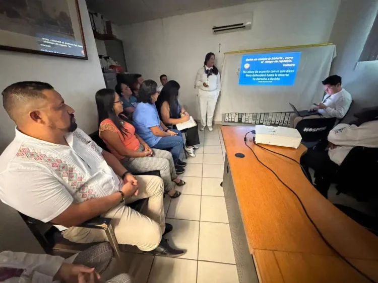 Grupo de trabajadores del ISSSTE en capacitación sobre violencia de género, con presentación en proyector y instructora.