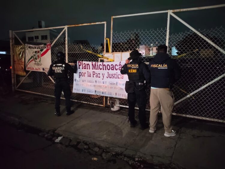 Agentes de Guardia Civil y Fiscalía observan cartel en entrada de un inmueble en la noche.