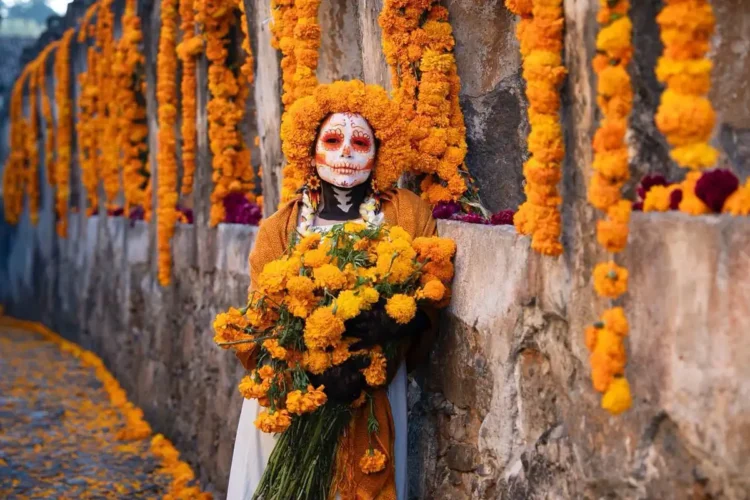 Muñeca con maquillaje de calavera y flores de cempasúchil en celebración de Día de Muertos en Michoacán.