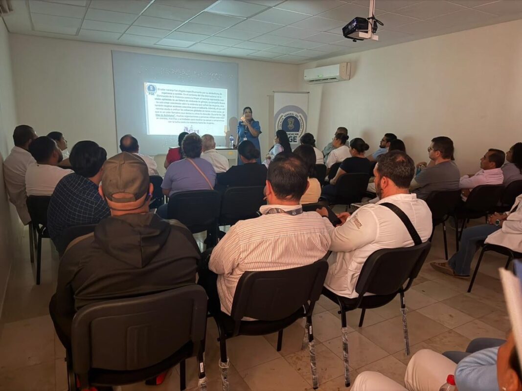 Funcionarios públicos en capacitación sobre seguridad en una sala de reuniones con proyector y pantalla.