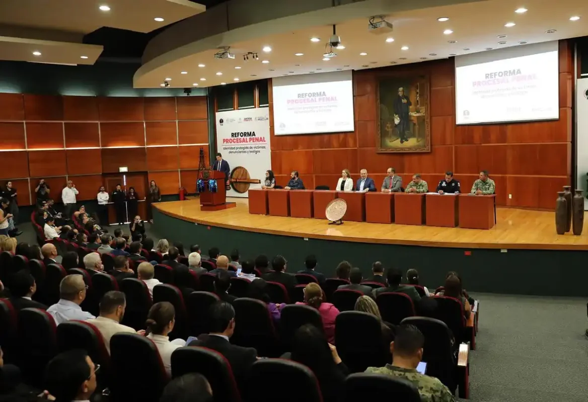 Auditorio con panel de expertos y público asistente en evento sobre reforma penal en Michoacán y Jalisco.