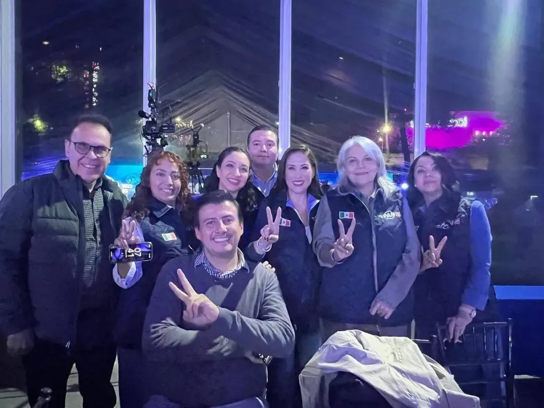 Grupo de políticos en Zamora posando con paz y unidad, algunos con signos de paz y sonrisas, en un ambiente nocturno.
