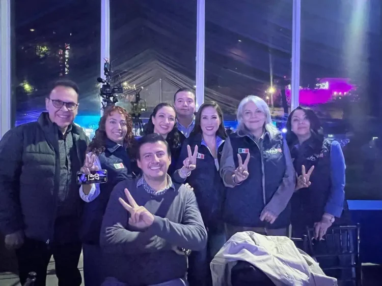 Grupo de políticos en Zamora posando con paz y unidad, algunos con signos de paz y sonrisas, en un ambiente nocturno.