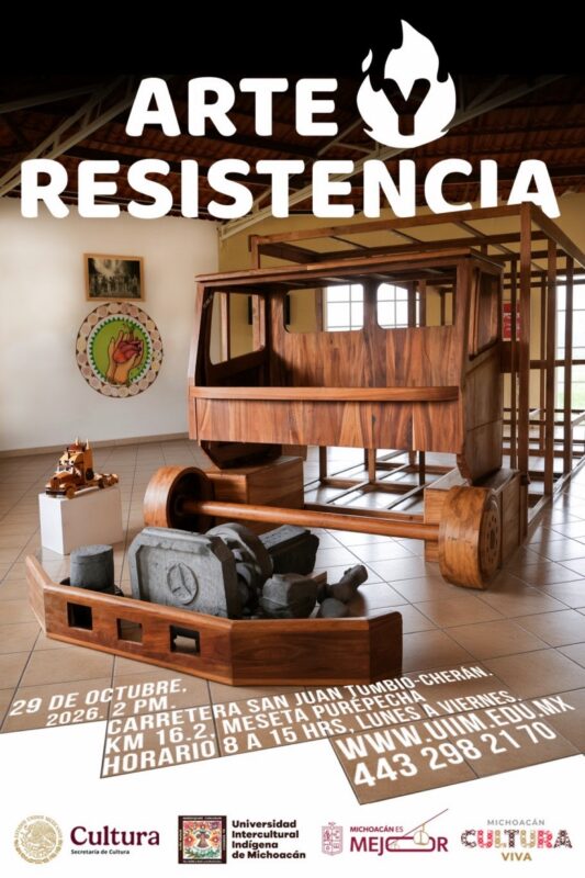 Exposición de esculturas de madera y piedra en una sala con paredes claras y techo de vigas metálicas.