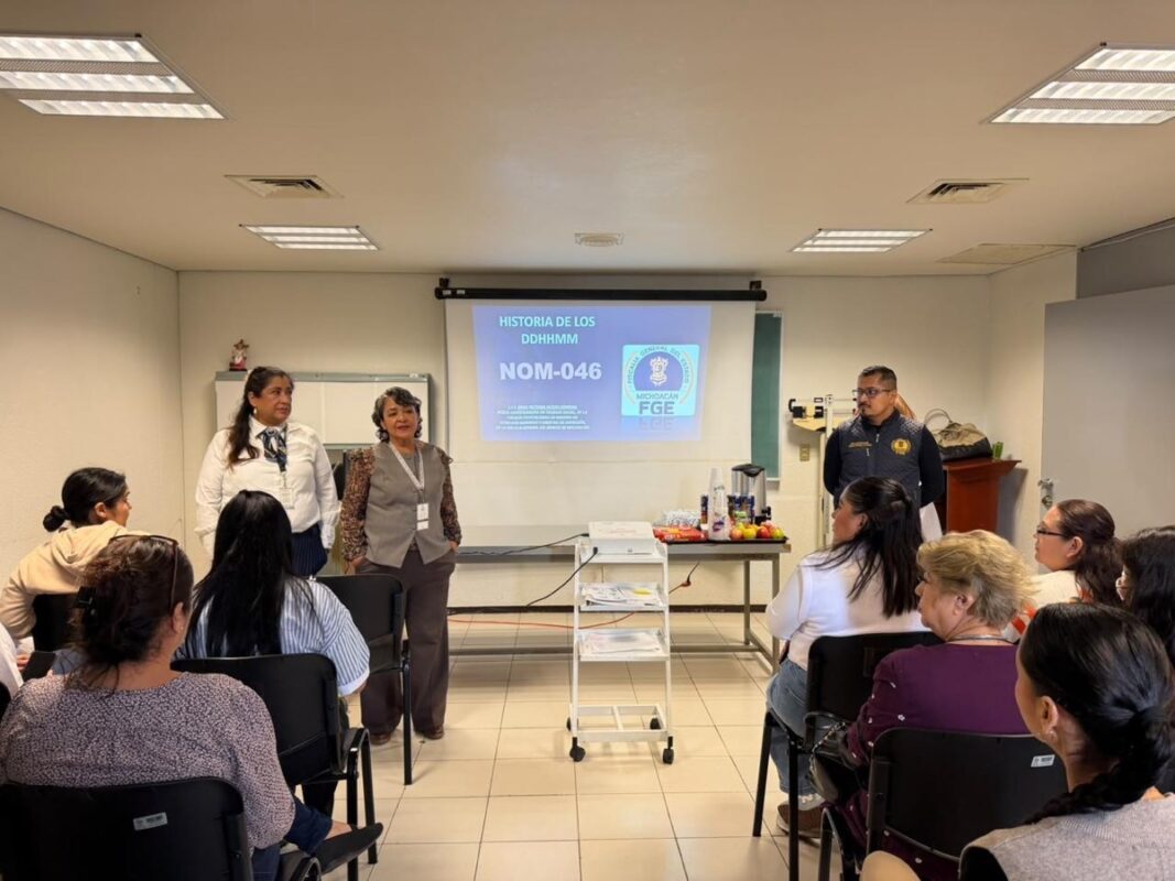 Un grupo de personas asiste a una presentación en un aula, con tres expositores frente a una pantalla que muestra una diapositiva titulada “NOM-046”.