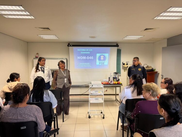 Un grupo de personas asiste a una presentación en un aula, con tres expositores frente a una pantalla que muestra una diapositiva titulada “NOM-046”.