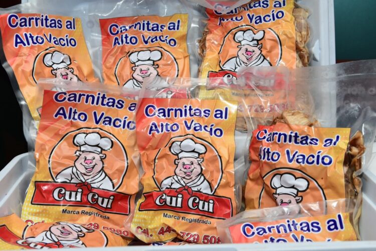 Paquetes de carnitas empacadas al vacío con un dibujo de un cerdito cocinero.