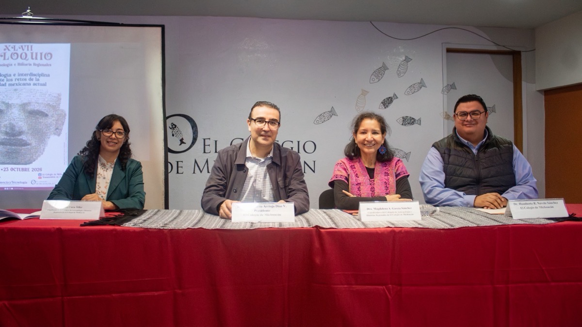 Cuatro personas sentadas detrás de una mesa con mantel rojo participan en un panel frente a un cartel y un fondo con dibujos de peces.