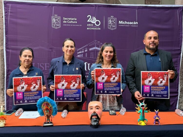 Cuatro personas posan sosteniendo carteles de un evento cultural frente a un fondo morado con logotipos de la Secretaría de Cultura de Michoacán.