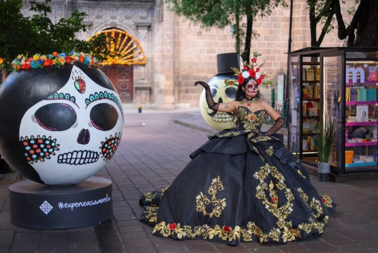Catrina con vestido negro posa entre calaveras decoradas en el Centro Histórico de Morelia durante Día de Muertos.
