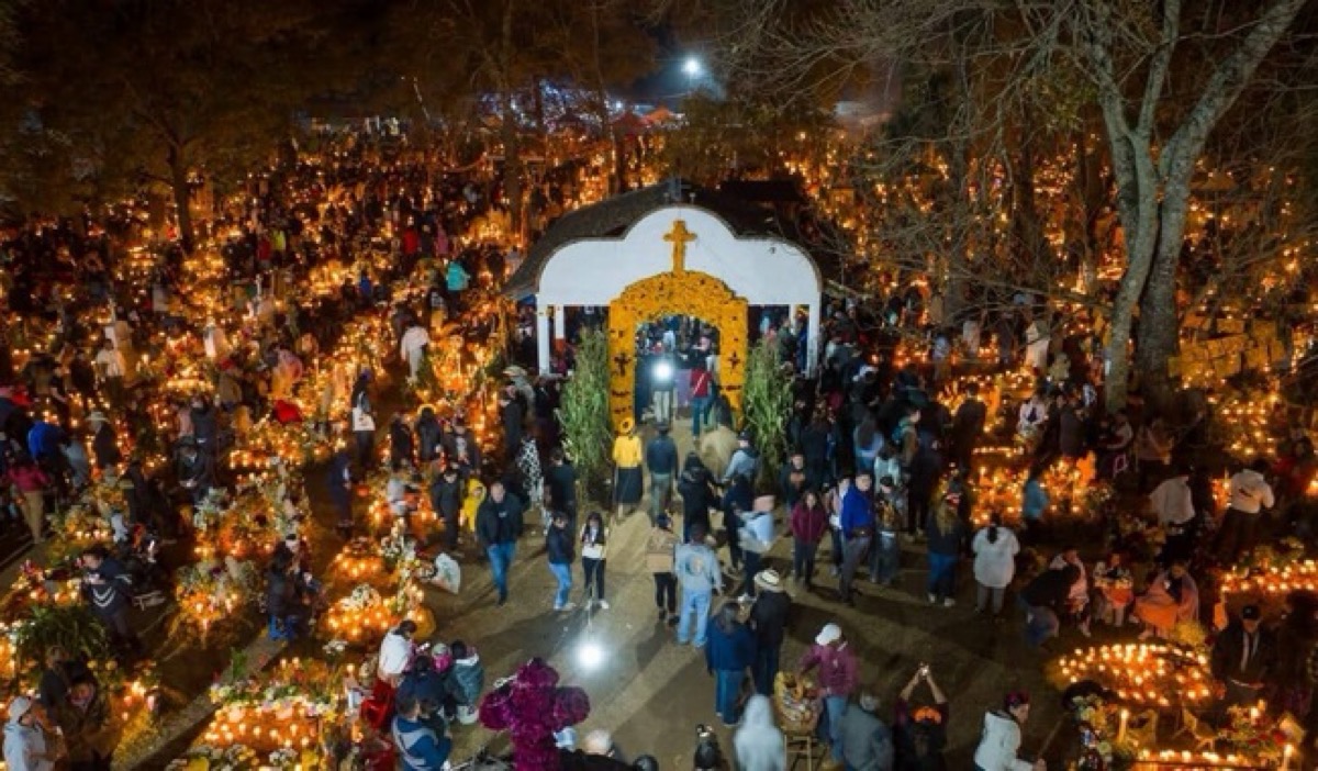 Multitud celebra la Noche de Ánimas en el cementerio de Pátzcuaro iluminado con velas.
