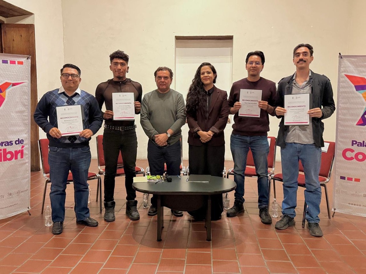 Seis personas posan en una sala, cinco de ellas sosteniendo certificados frente a banners coloridos.