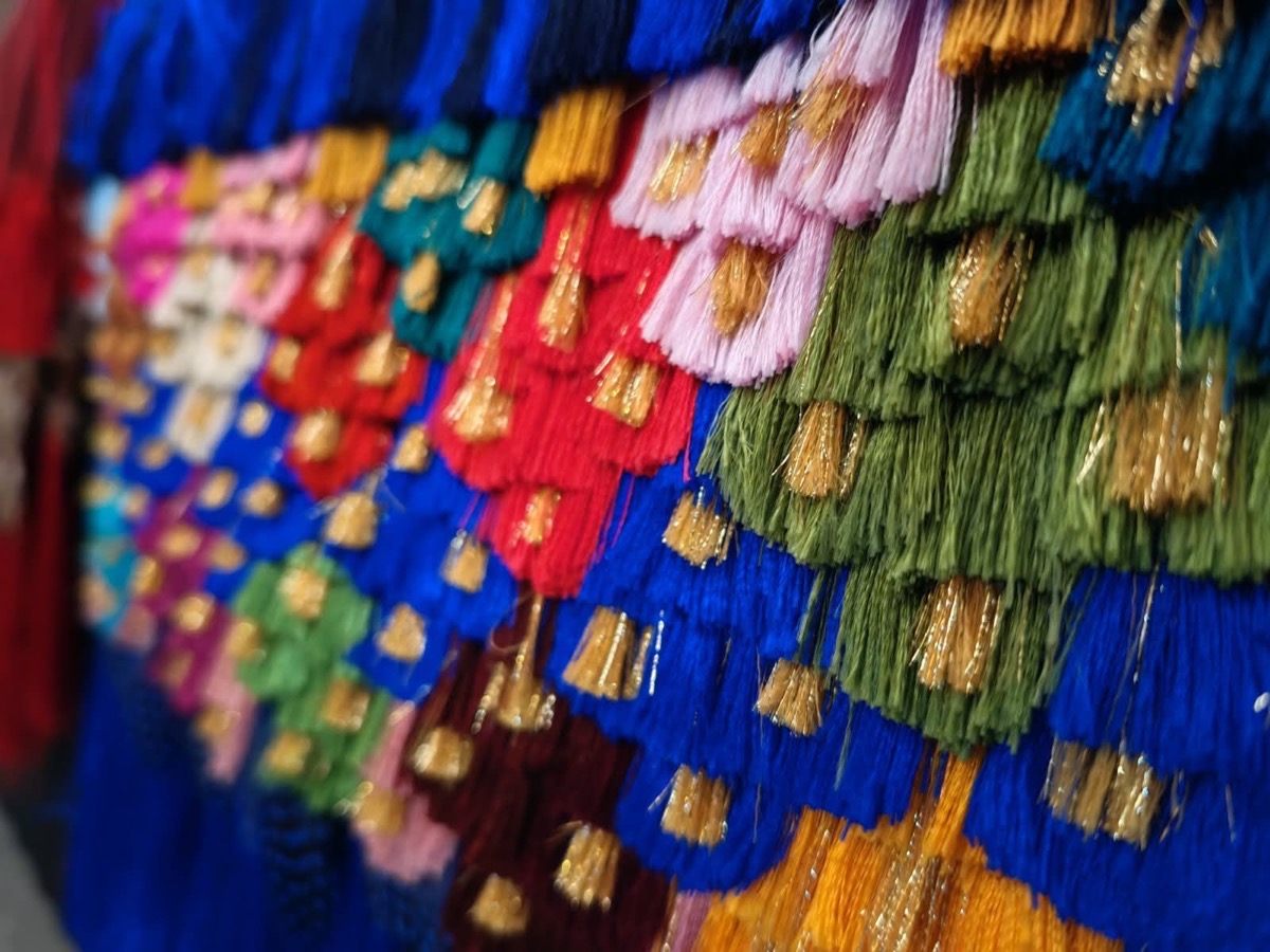 Un conjunto de borlas de hilos de colores brillantes dispuestas en filas superpuestas.
