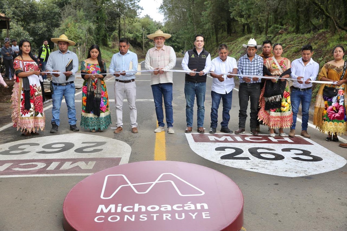 Un grupo de personas corta una cinta en la inauguración de un tramo de carretera rodeado de árboles.