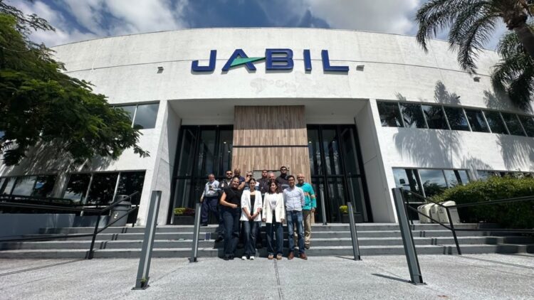 Un grupo de personas está de pie en las escaleras frente a un edificio con el letrero "Jabil".