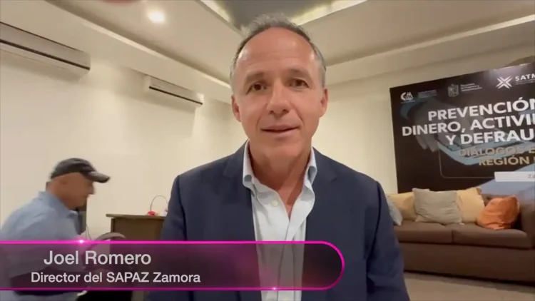 Joel Romero, director del SAPAZ Zamora, en una conferencia en una sala de reuniones con banner informativo de fondo.