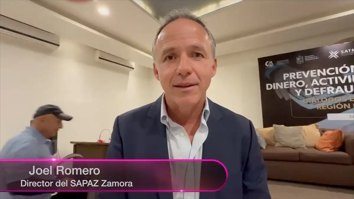 Joel Romero, director del SAPAZ Zamora, en una conferencia en una sala de reuniones con banner informativo de fondo.